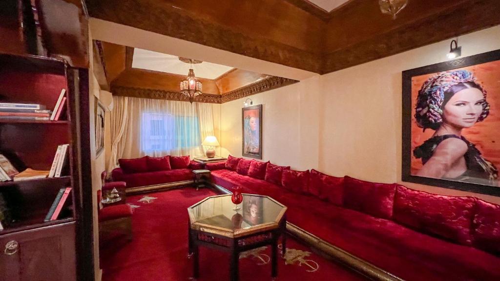 Flair's Family Apartment في مراكش: غرفة معيشة بها أريكة حمراء و لوحة