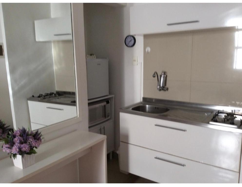 a white kitchen with a sink and a refrigerator at Lindo Studio Ipanema in Rio de Janeiro