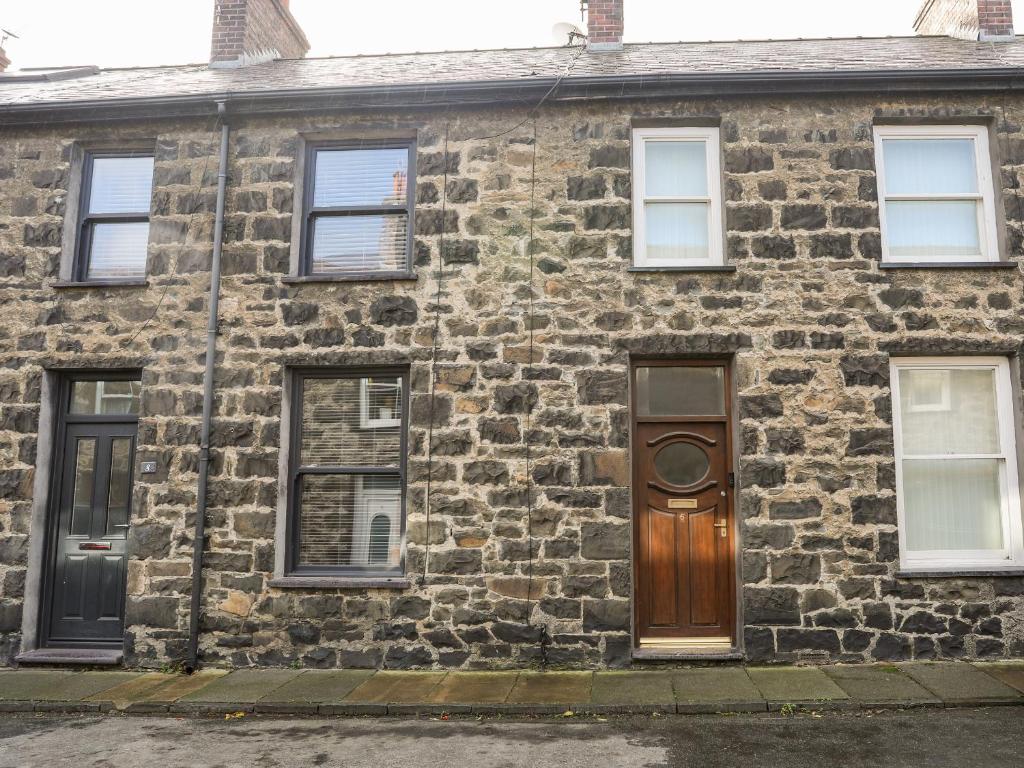 a stone house with a wooden door and windows at 6 Erasmus Street in Penmaen-mawr
