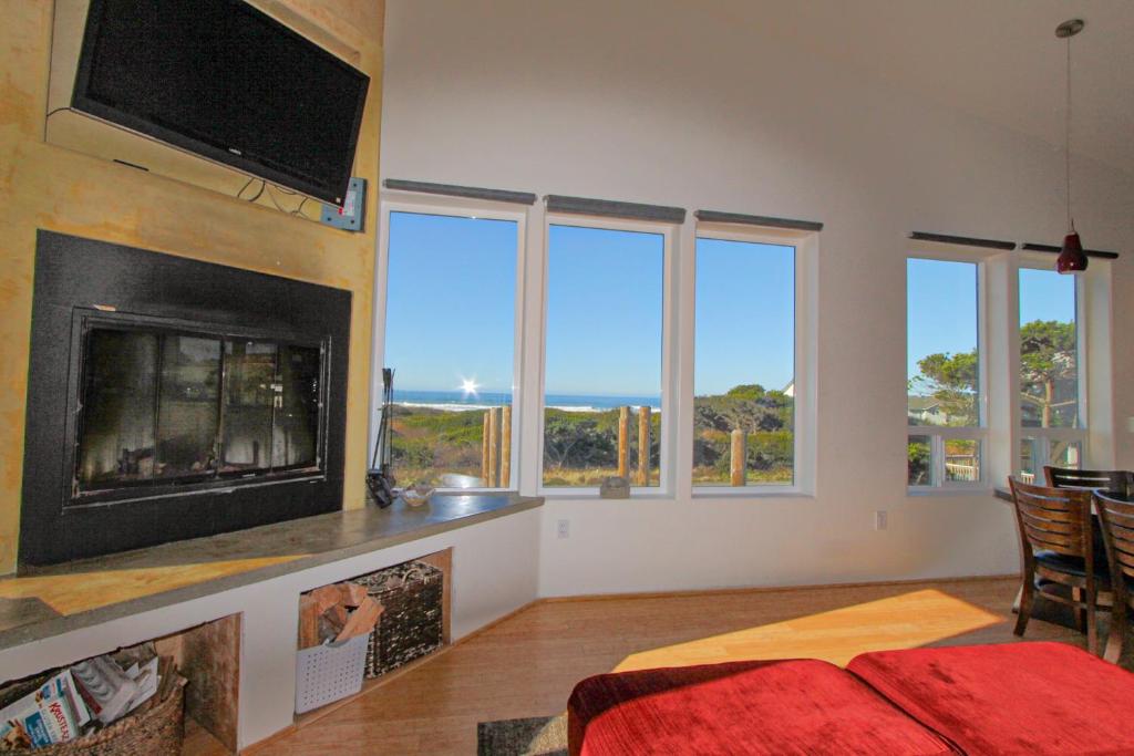 a bedroom with a fireplace and a tv and windows at Sand Crab in Gold Beach