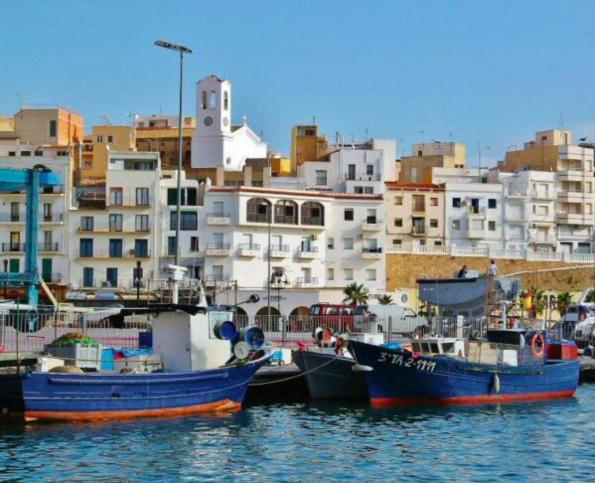 twee boten zijn aangemeerd in een haven met gebouwen bij Apt Familiar con vistas al mar in L'Ametlla de Mar