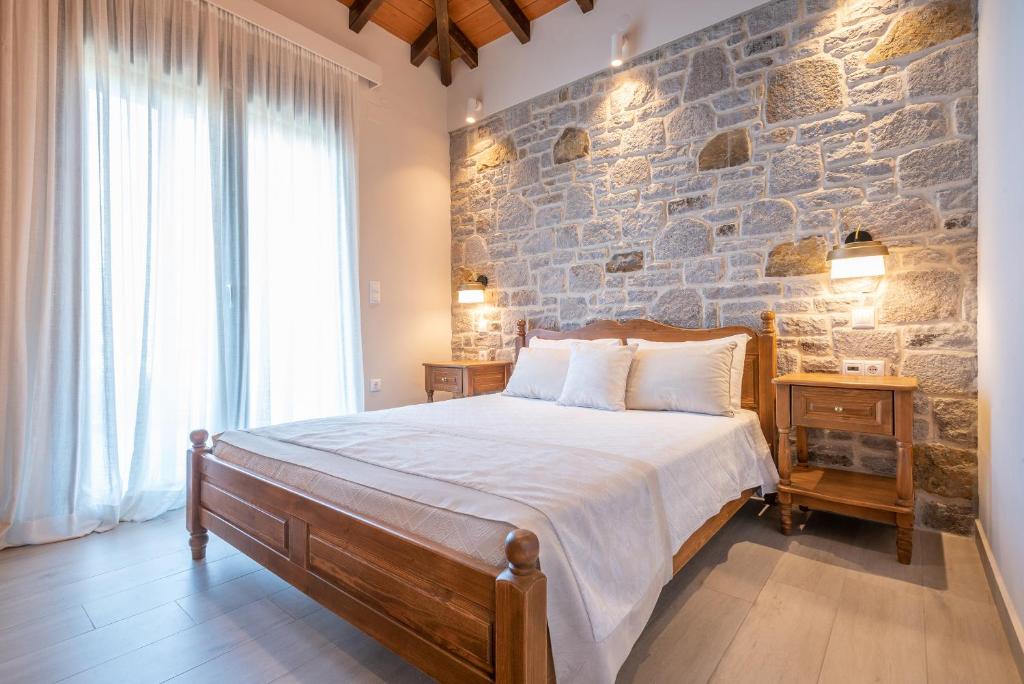 a bedroom with a large bed with a stone wall at Amigdalies in Myrina