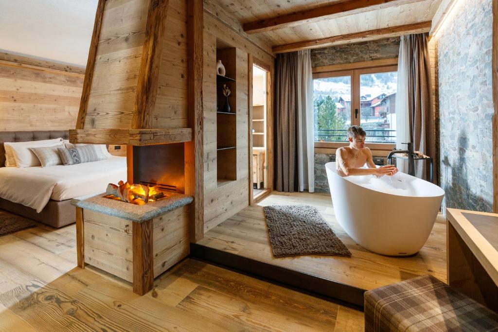 a woman sitting in a bath tub in a bedroom at Sci Sport rooms & suites in Bormio