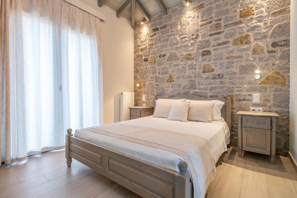 a bedroom with a large bed and a stone wall at Amigdalies in Myrina