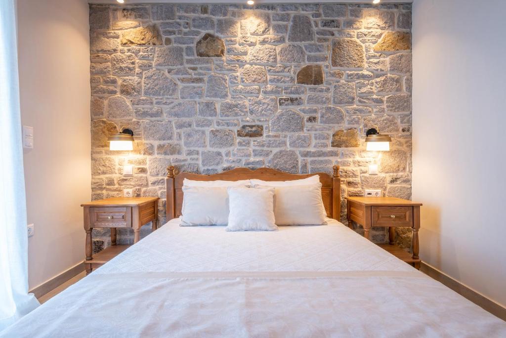 a bedroom with a bed and a stone wall at Amigdalies in Myrina