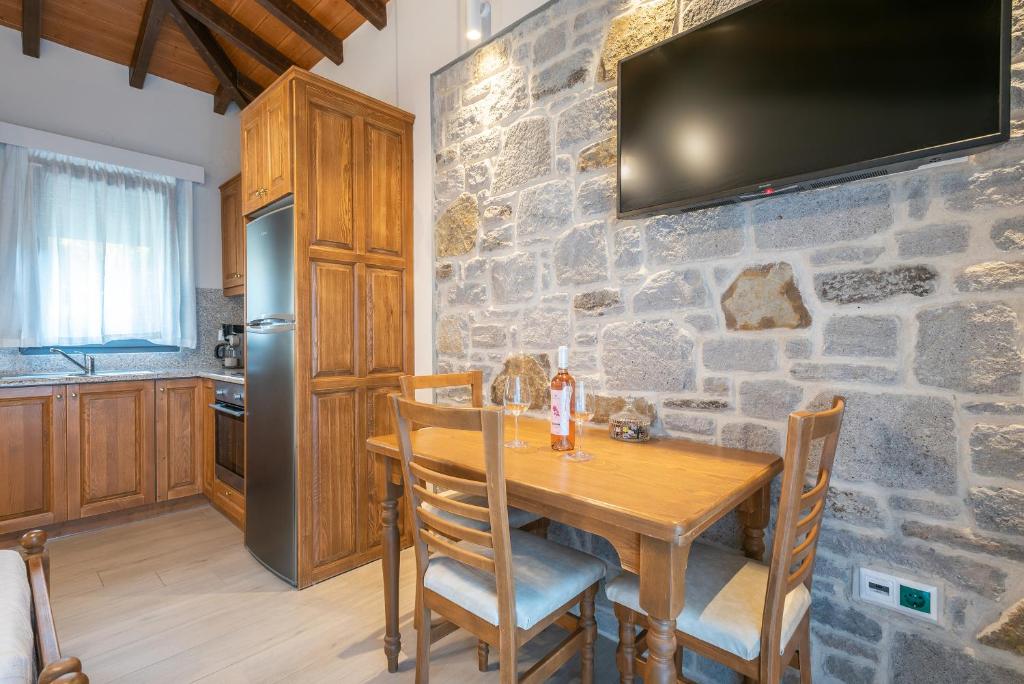 a kitchen with a wooden table and a tv on a stone wall at Amigdalies in Myrina