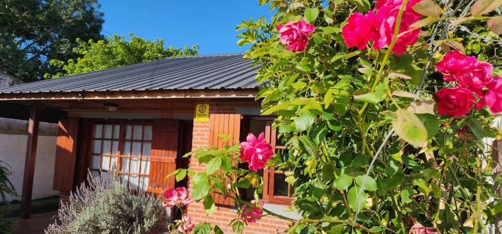 una casa con flores rosas delante de ella en Mi casita en Miramar