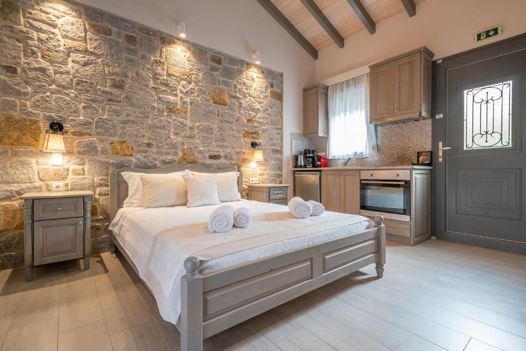 a bedroom with a large bed and a stone wall at Amigdalies in Myrina