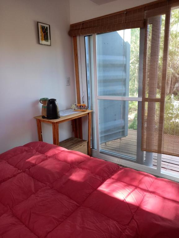 Un dormitorio con una gran cama roja y una ventana en Aguaymanto, en Cuchilla Alta