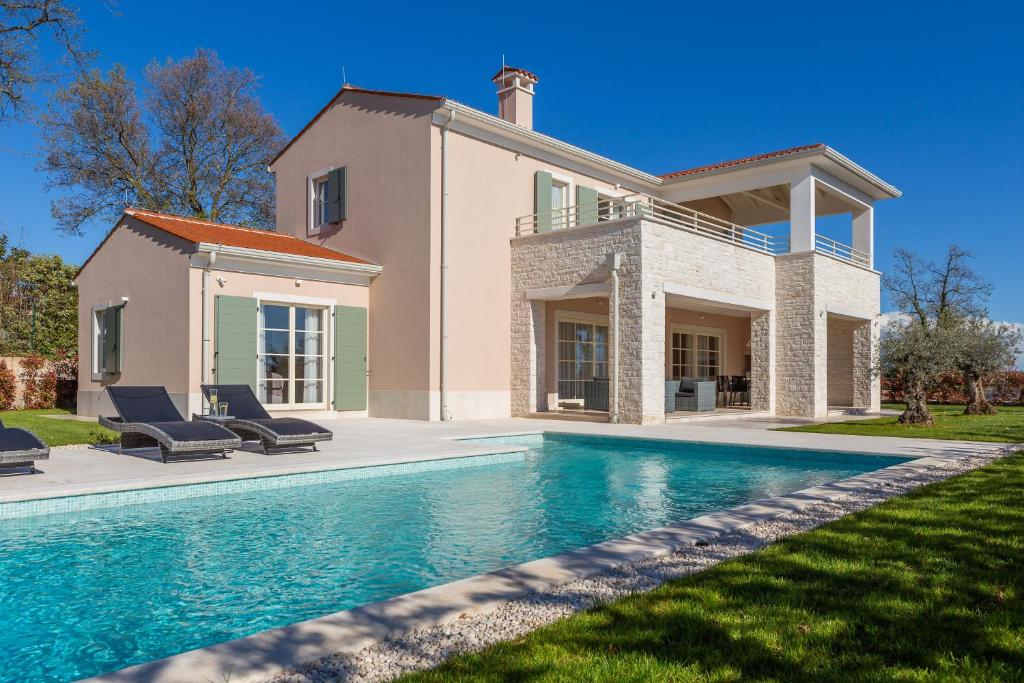 une maison avec une piscine en face d'une maison dans l'établissement Villa Iris by ILC (Istria Luxury Collection), à Brtonigla