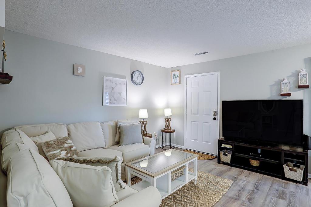 a living room with a white couch and a tv at Waccamaw Condo - Unit 6 in Myrtle Beach