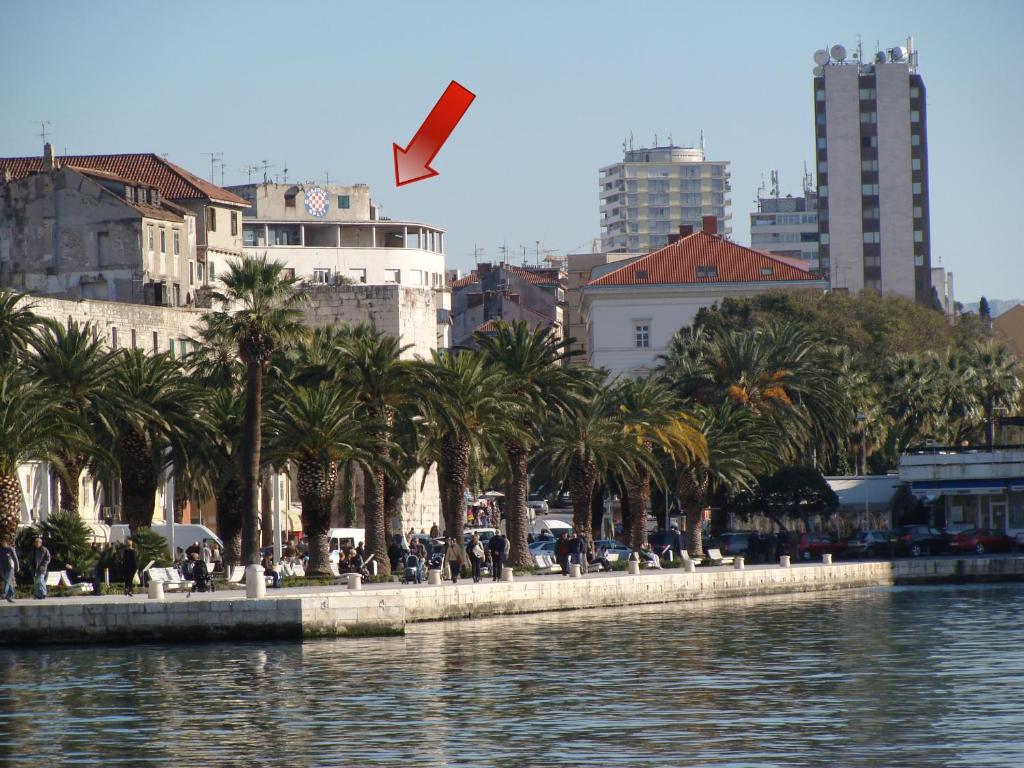 a kite flying over a body of water with palm trees at Diocletian Apartments & Rooms in Split