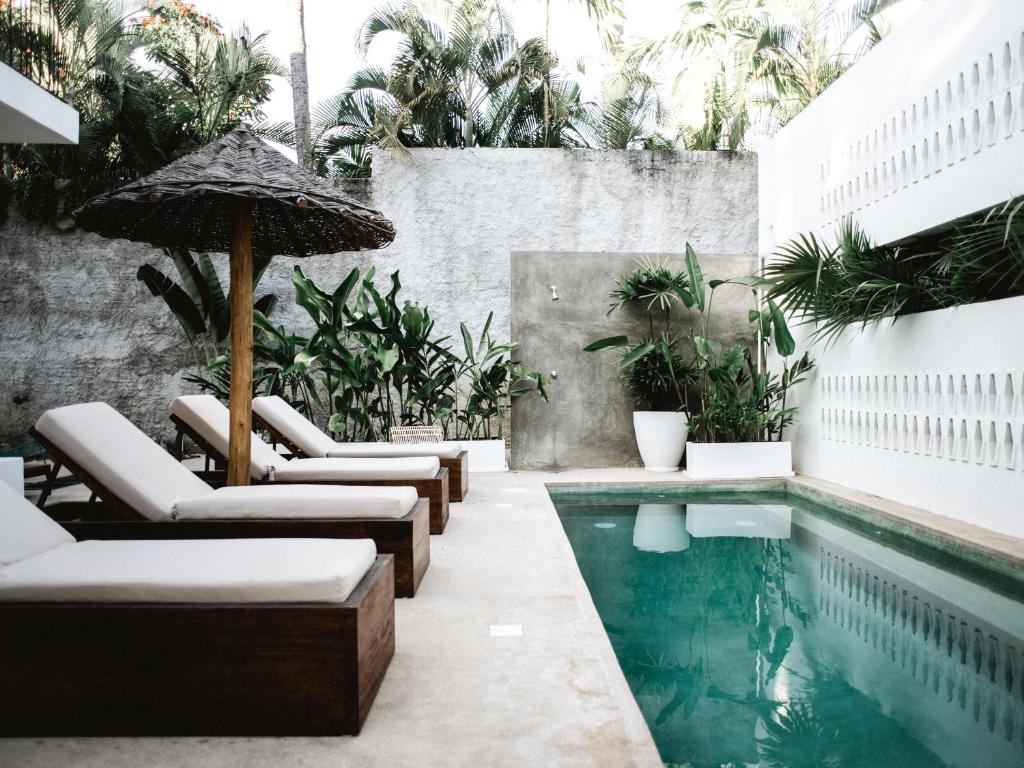 a swimming pool with lounge chairs and an umbrella at Residencia Tropical Don Bonito in Sayulita