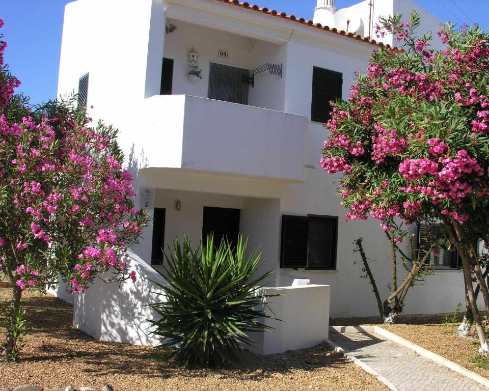 un edificio bianco con fiori rosa di fronte di Retur Algarve Beach House a Castro Marim