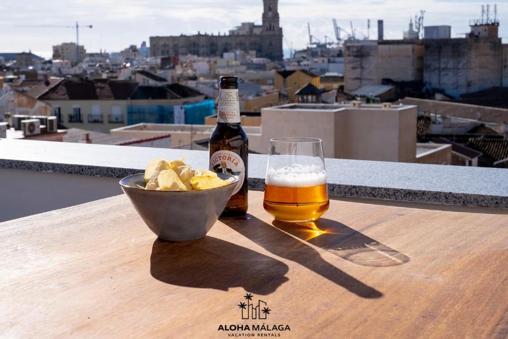 a bottle of beer and a bowl of chips and a glass of beer at Luxury Duplex with Pool and Padel Court in Town by AlohaMálaga in Málaga