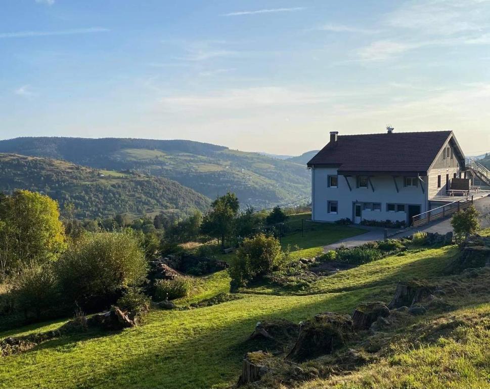 une maison blanche sur une colline avec un champ herbeux dans l'établissement Le Gîte de mon grand père, à La Bresse