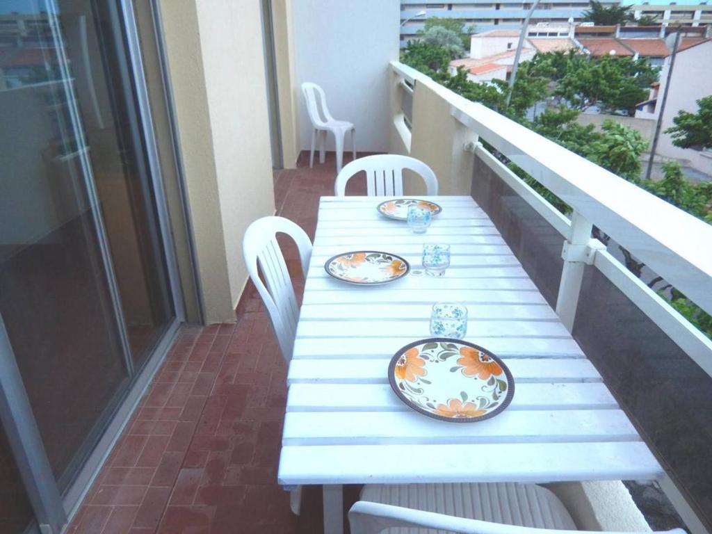 une table blanche avec des plaques sur le balcon dans l'établissement Appartement 3 pièces, 6 couchages, proche plage et centre, balcon, classé 2 étoiles, ménage inclus - FR-1-229C-608, à Port-la-Nouvelle