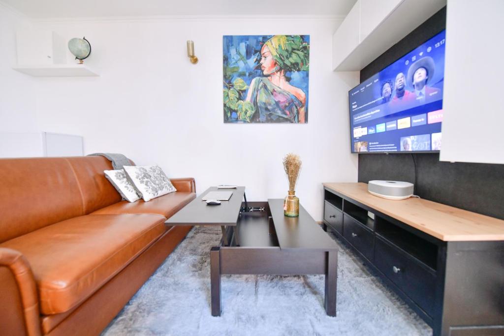 salon z brązową skórzaną kanapą i telewizorem w obiekcie Paris La Villette - Charming Apartment 2 rooms w Paryżu