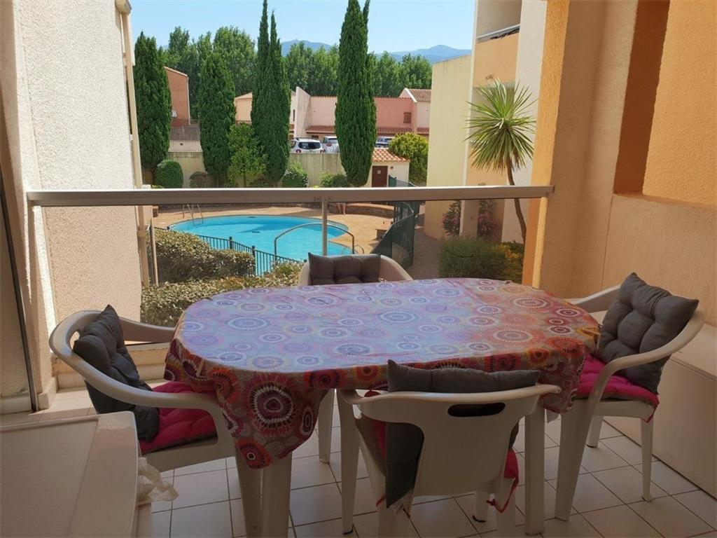 d'un balcon avec une table, des chaises et une piscine. dans l'établissement Charmant T2 avec Piscine et Parking Privé, Proche Plage et Centre, Argelès-sur-Mer - FR-1-388-88, à Argelès-sur-Mer