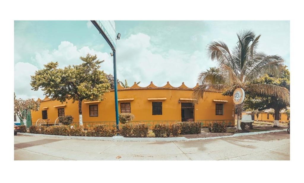 a yellow building with palm trees in front of it at Casa Colonial in Mariquita
