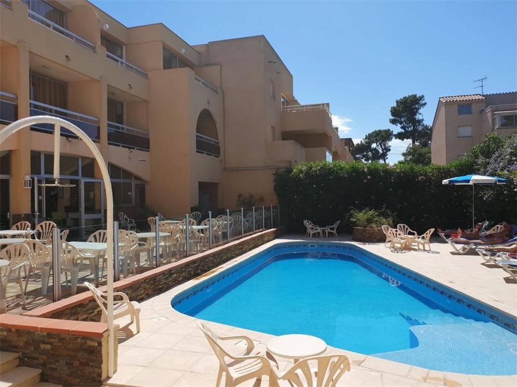 une piscine avec des chaises et un bâtiment dans l'établissement Appartement T2 climatisé avec terrasse, proche plage à Argelès-sur-Mer, parking et piscine inclus - FR-1-388-202, à Argelès-sur-Mer