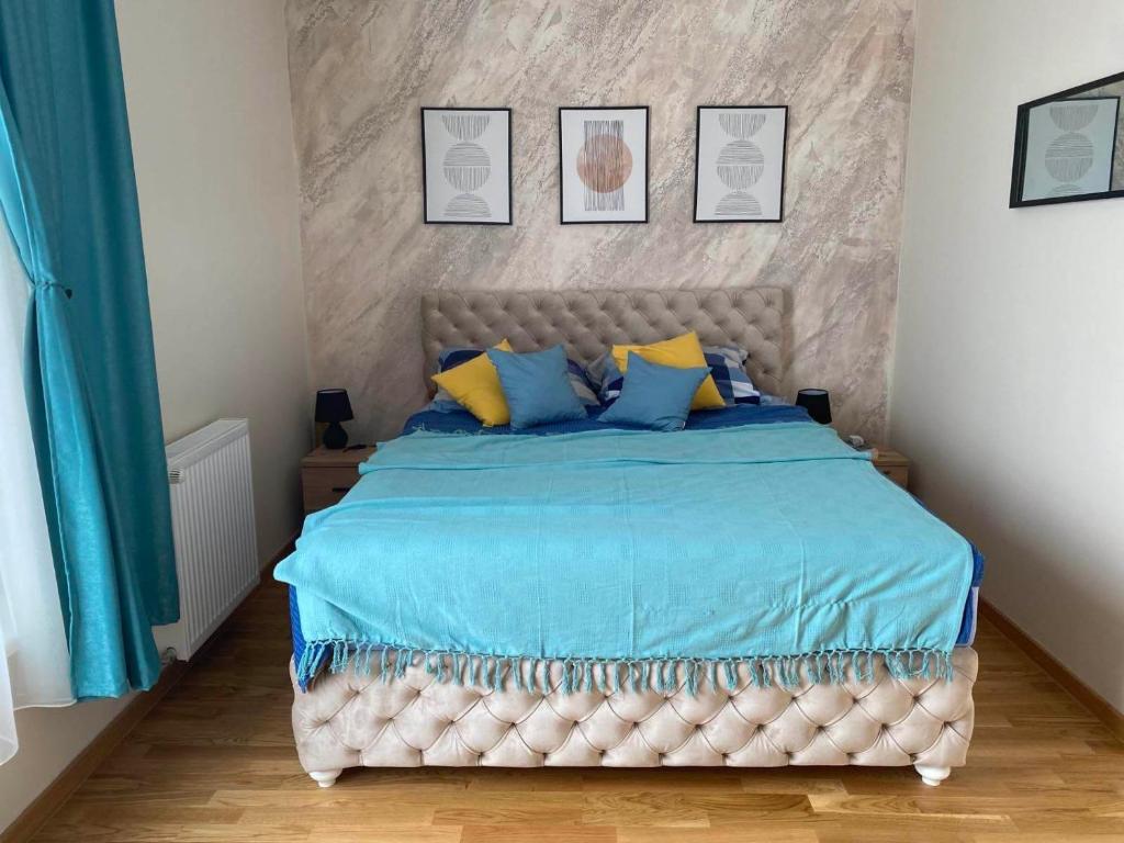 Schlafzimmer mit einem Bett mit blauen und gelben Kissen in der Unterkunft Belgrade Balcony in Belgrad
