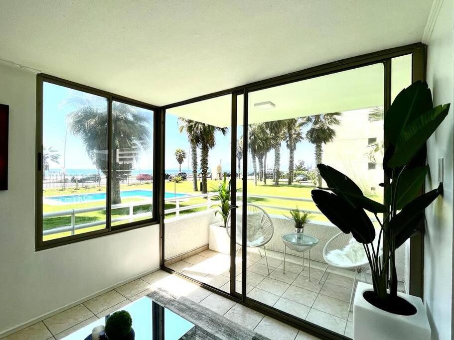 een kamer met ramen en uitzicht op een zwembad bij La Serena - Departamento Frente al Mar in La Serena