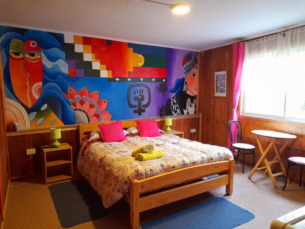 a bedroom with a bed with a painting on the wall at Hostal Destino Bellavista in Valparaíso