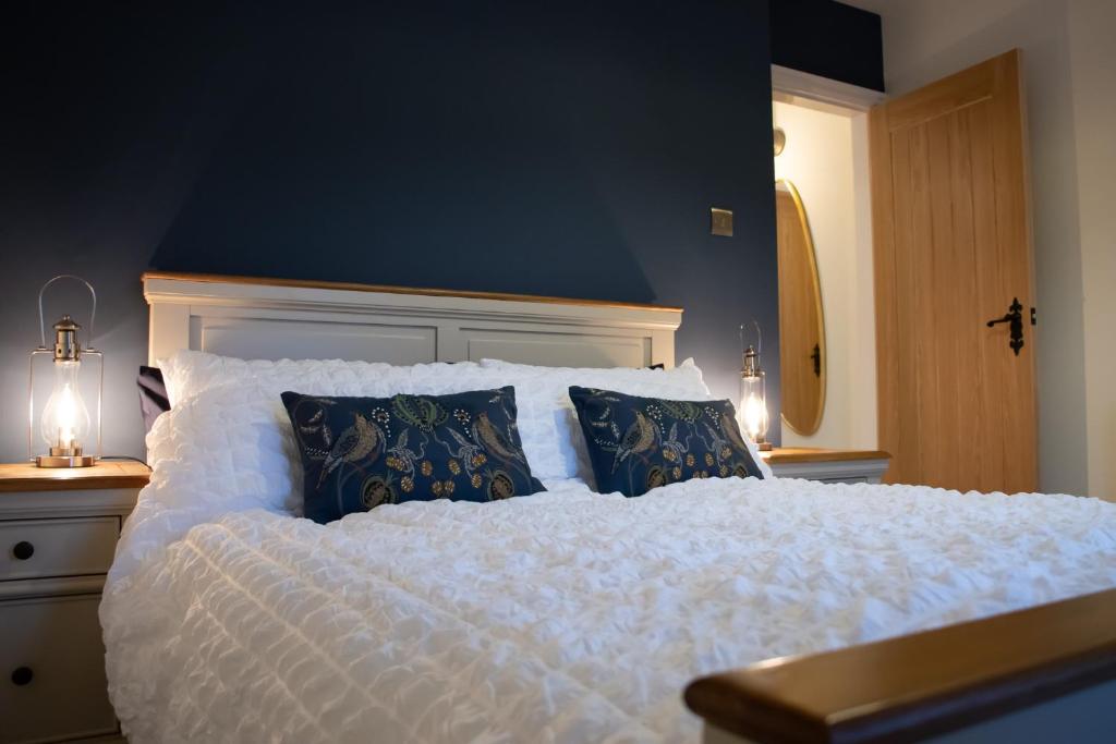 a bedroom with a large white bed with blue walls at The Burrow in Kelso