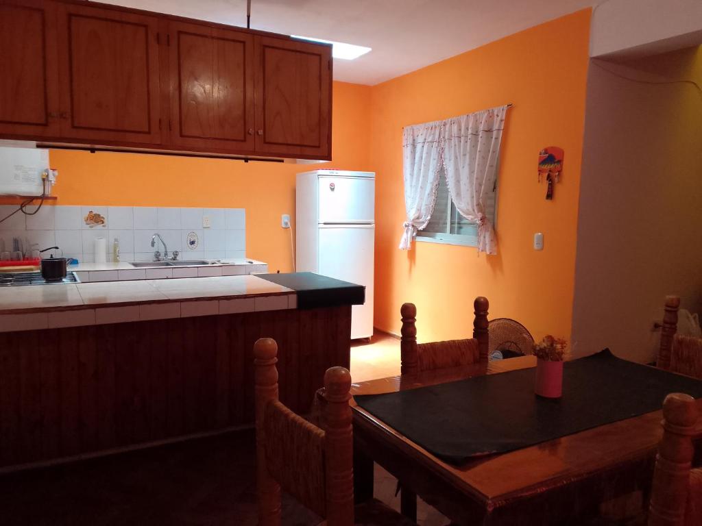 a kitchen with a table and a white refrigerator at La Casa de la Parra in Villa Carlos Paz