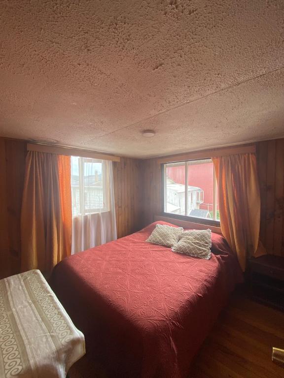 a bedroom with a red bed with two pillows on it at Mi casa chilota in Ancud