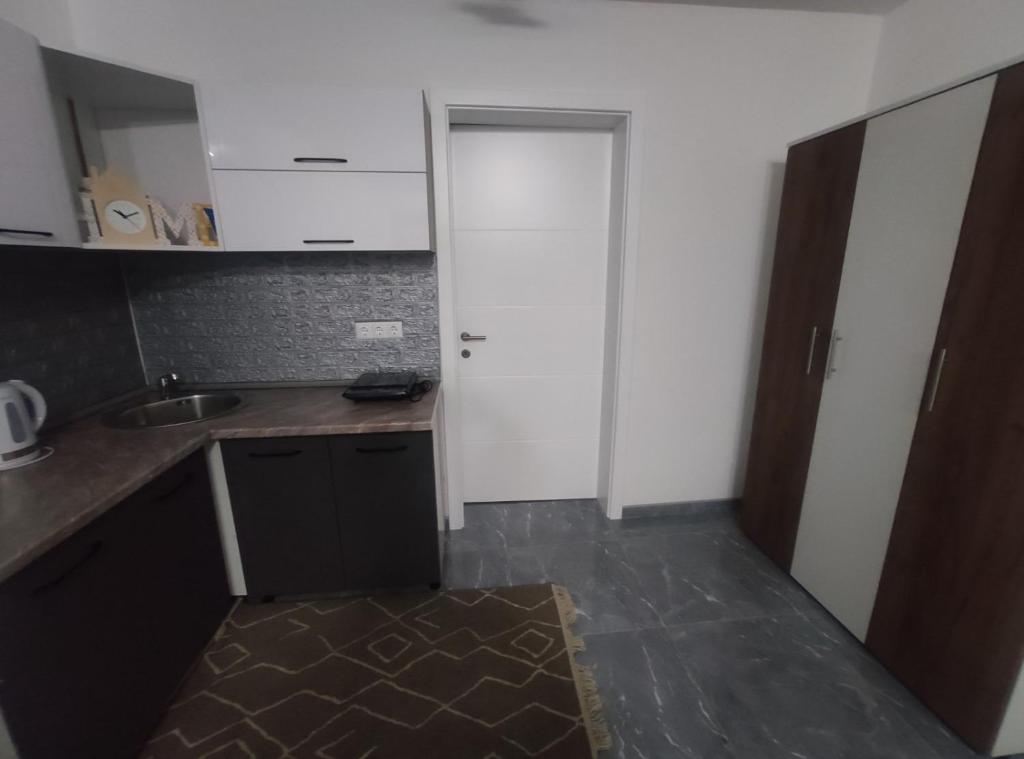uma pequena cozinha com uma porta branca e um lavatório em NEER em Živinice