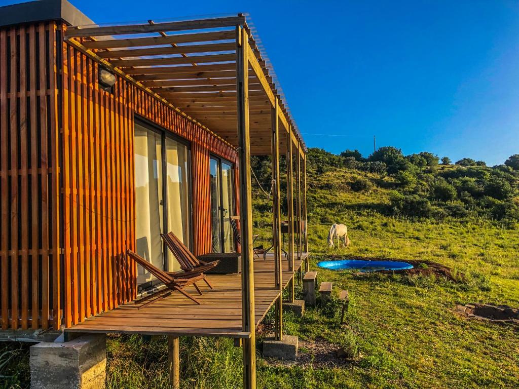 a house with a deck and a horse in a field at Bungalow de campo Torero - sierras, naturaleza y relax in Minas