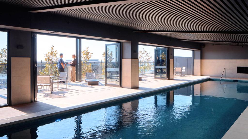- une piscine dans un bâtiment avec des personnes debout à l'extérieur dans l'établissement Mercure Melbourne Doncaster, à Doncaster