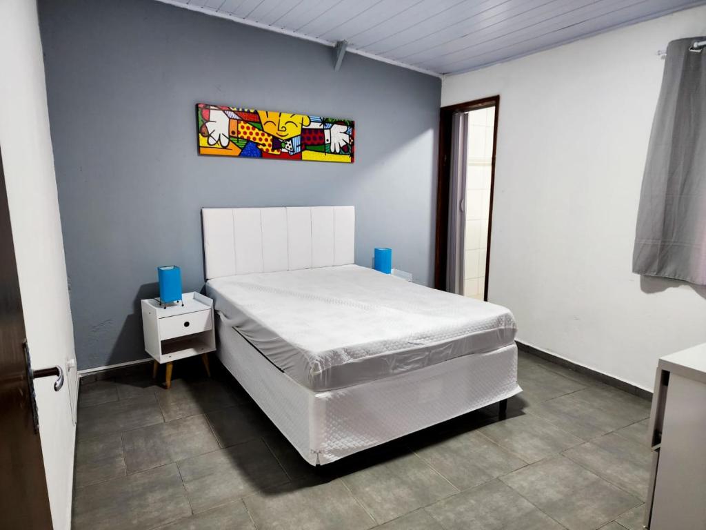 1 dormitorio con 1 cama blanca en una pared azul en Aloha Casa em Ilhabela, en Ilhabela