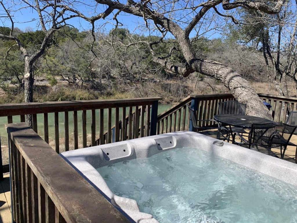 a hot tub on a deck with a table at Bandera Stronghold - Crazy Horse Cabin in Bandera
