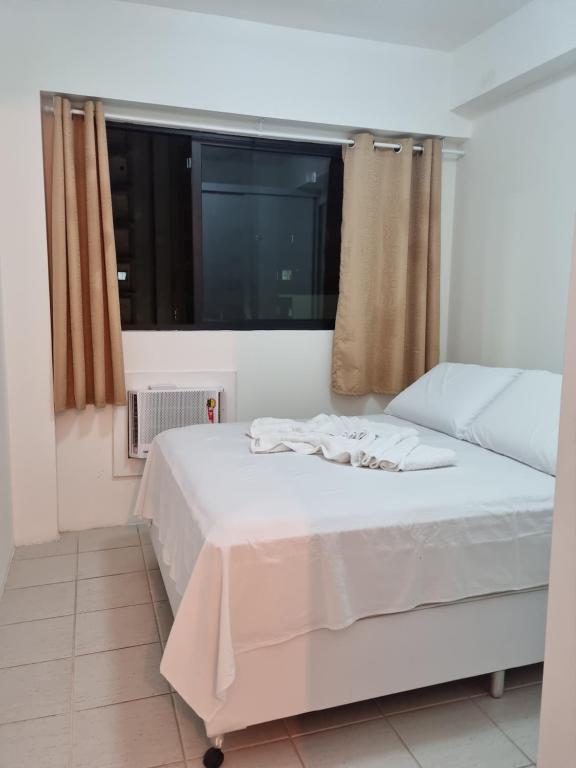 a white bed in a room with a window at BOA VIAGEM FLAT 106 in Recife
