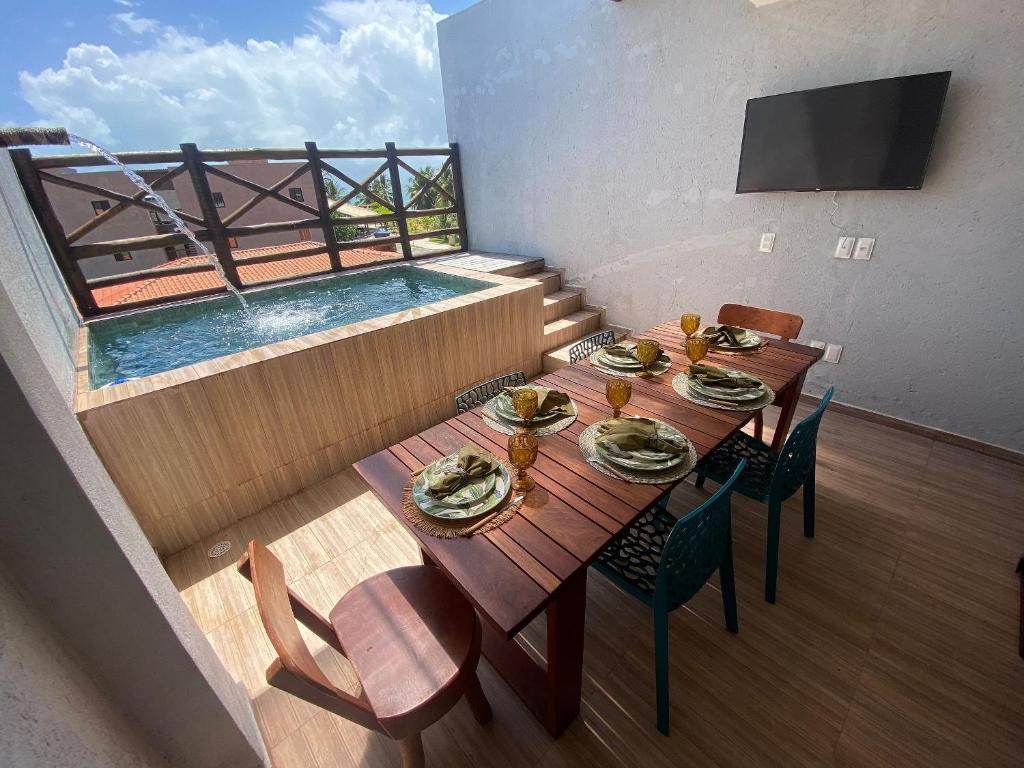 a balcony with a table and a swimming pool at Casa Coralli Milagres ER Hospedagens in São Miguel dos Milagres