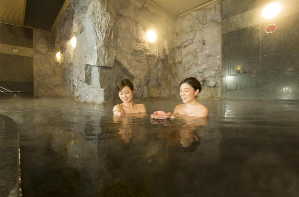 Dos mujeres en un jacuzzi con agua en Premier Hotel -CABIN- Obihiro, en Obihiro