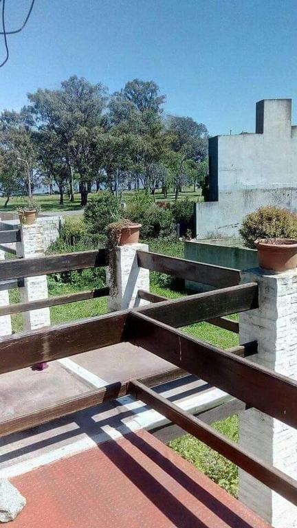 un banco de madera sentado junto a una valla en Las moras en Chascomús