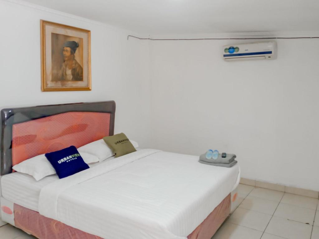 Urbanview Hotel Rio Life House Cianjur by RedDoorz في سيانجور: سرير في غرفة مع صورة على الحائط