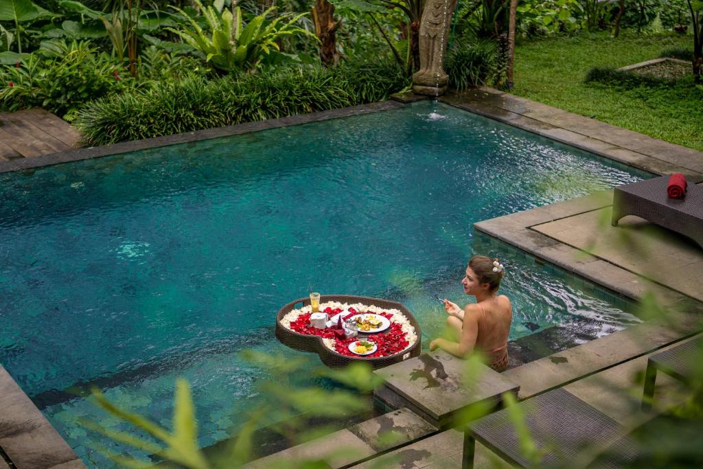 a man in a swimming pool with a tray of food at Villa Ubud Sunshine in Ubud