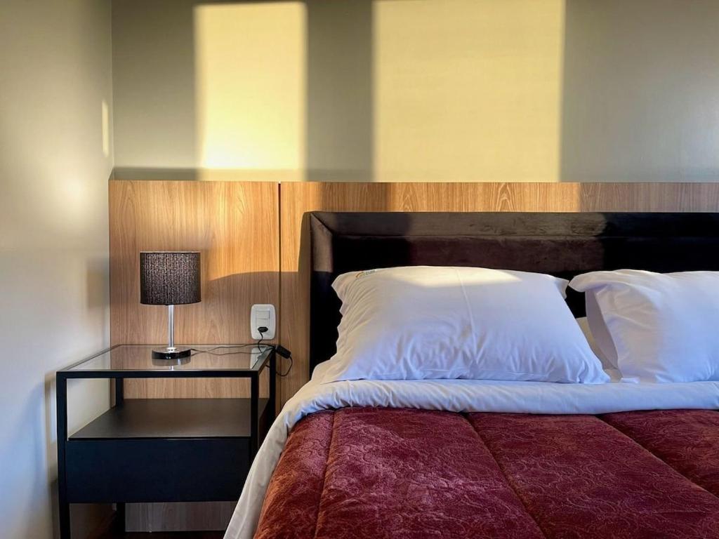 1 cama con cabecero de madera y mesita de noche con lámpara en MARAVILHOSO Apartamento VISTA DO VALE e 2 dorm, en Gramado
