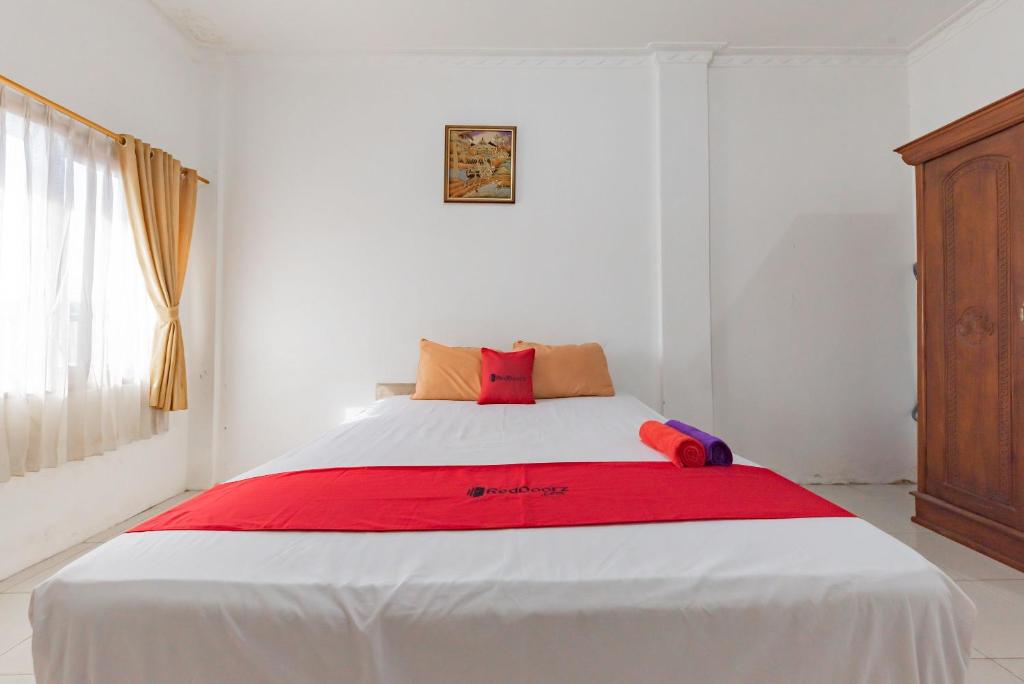 a bedroom with a large bed with a red blanket at RedDoorz near Samarinda Square in Samarinda