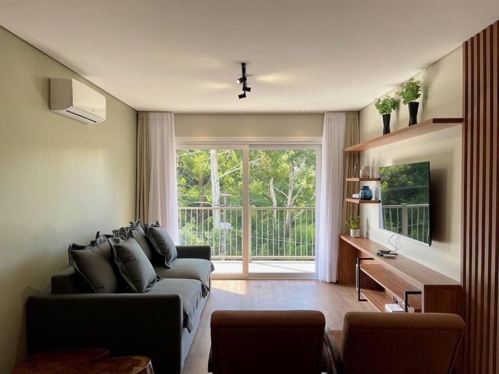 a living room with a couch and a large window at Apartamentos Quinta do Palácio by Achei Gramado in Canela