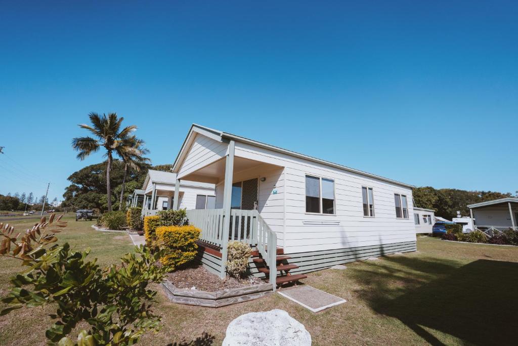 a white house with a porch and a palm tree at BIG4 Breeze Holiday Parks - Bargara in Bargara