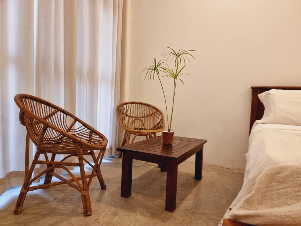 um quarto com uma mesa e duas cadeiras e uma planta em Sandil Surf house em Ahangama