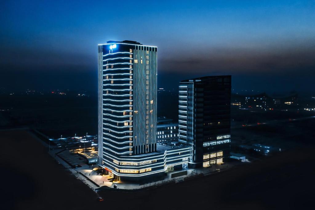 un edificio alto con luces encima por la noche en Shanxi Xiaohe Xincheng Talent Apartment en Taiyuán