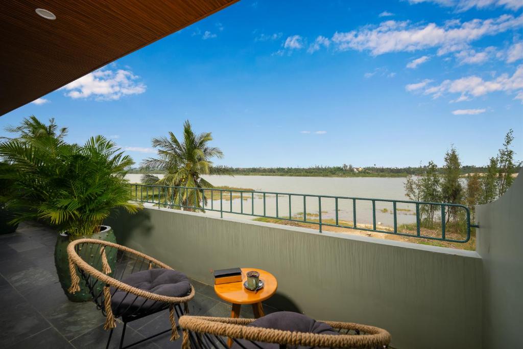 a balcony with a table and chairs and a view of the water at Bon Sand Villa & Spa Hoi An in Hoi An
