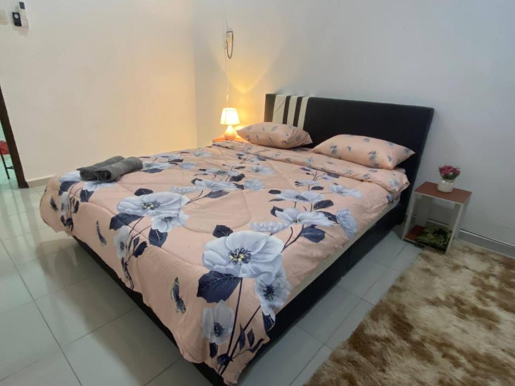 a bed with a floral comforter and pillows in a bedroom at Islamic Homestay Promenade Tanjung Lumpur in Kuantan